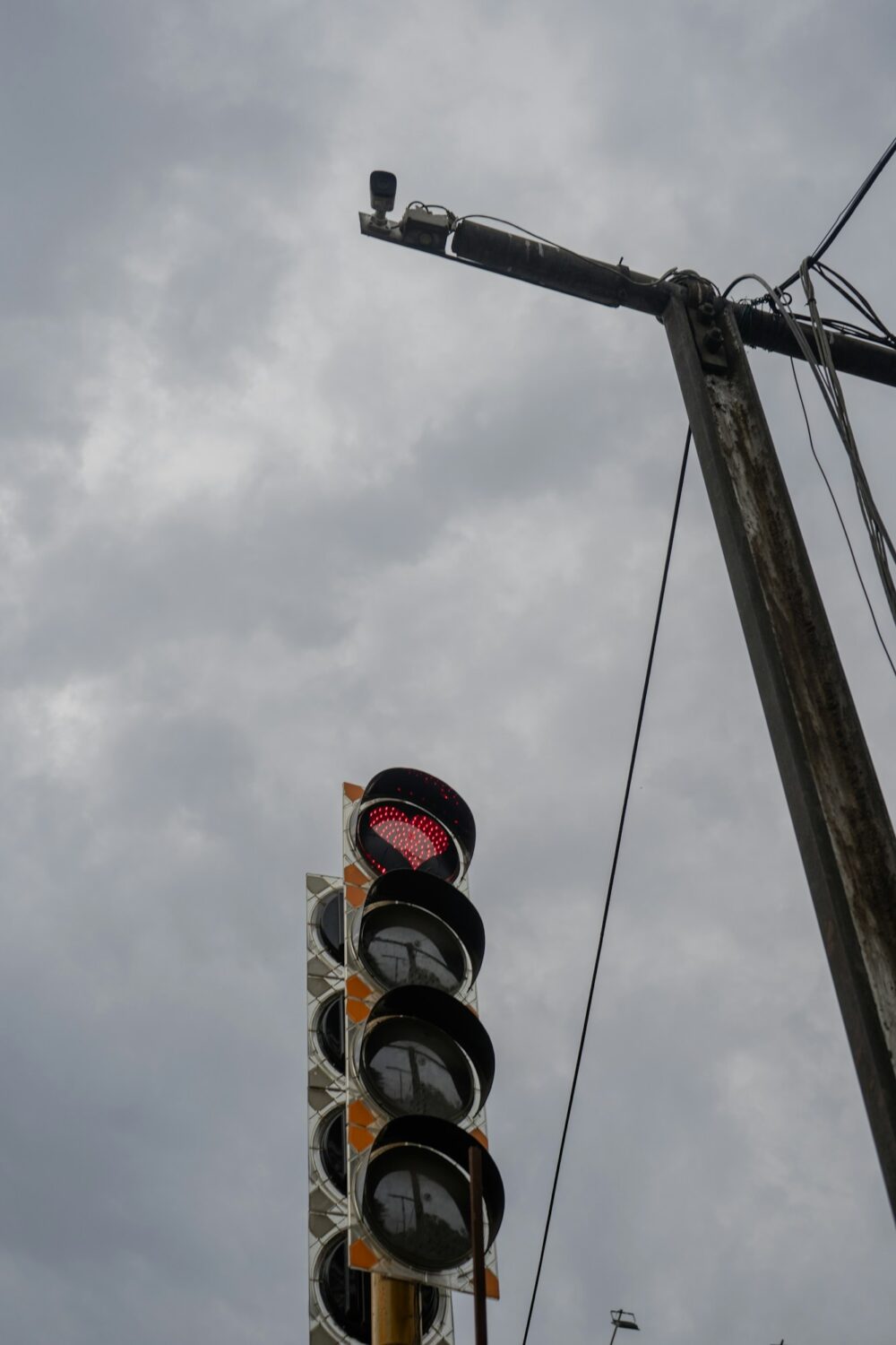 A traffic light on a pole with a cloudy sky in the background